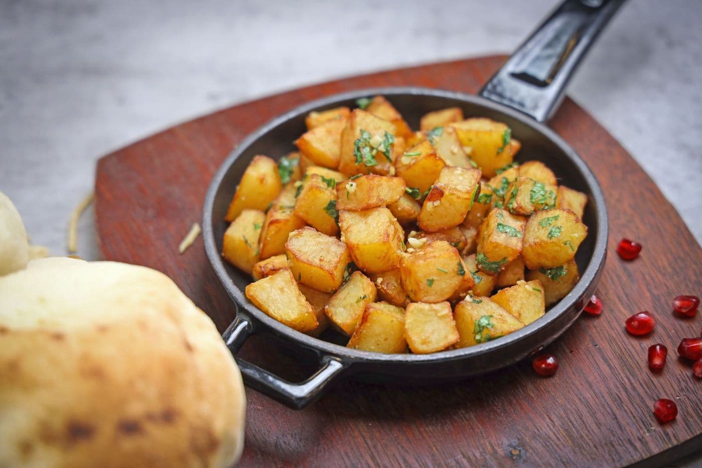Delicious crispy fried potatoes seasoned with herbs served in an iron skillet with bread.